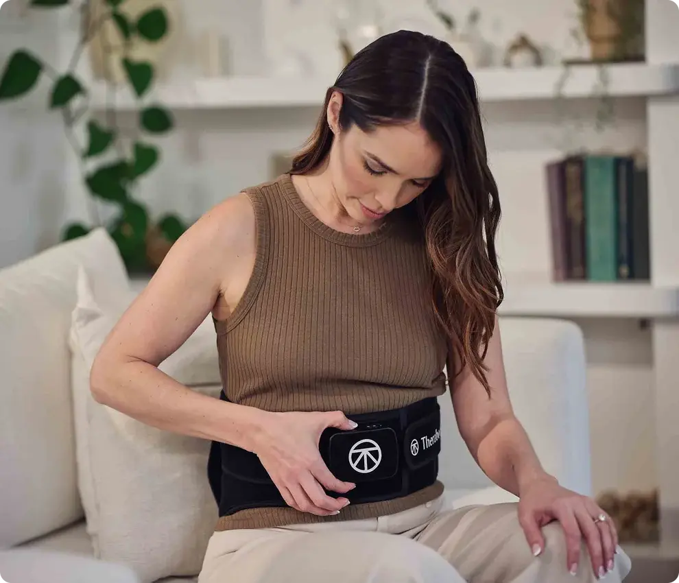 Woman wearing and adjusting Therabody ThermBack LED at home